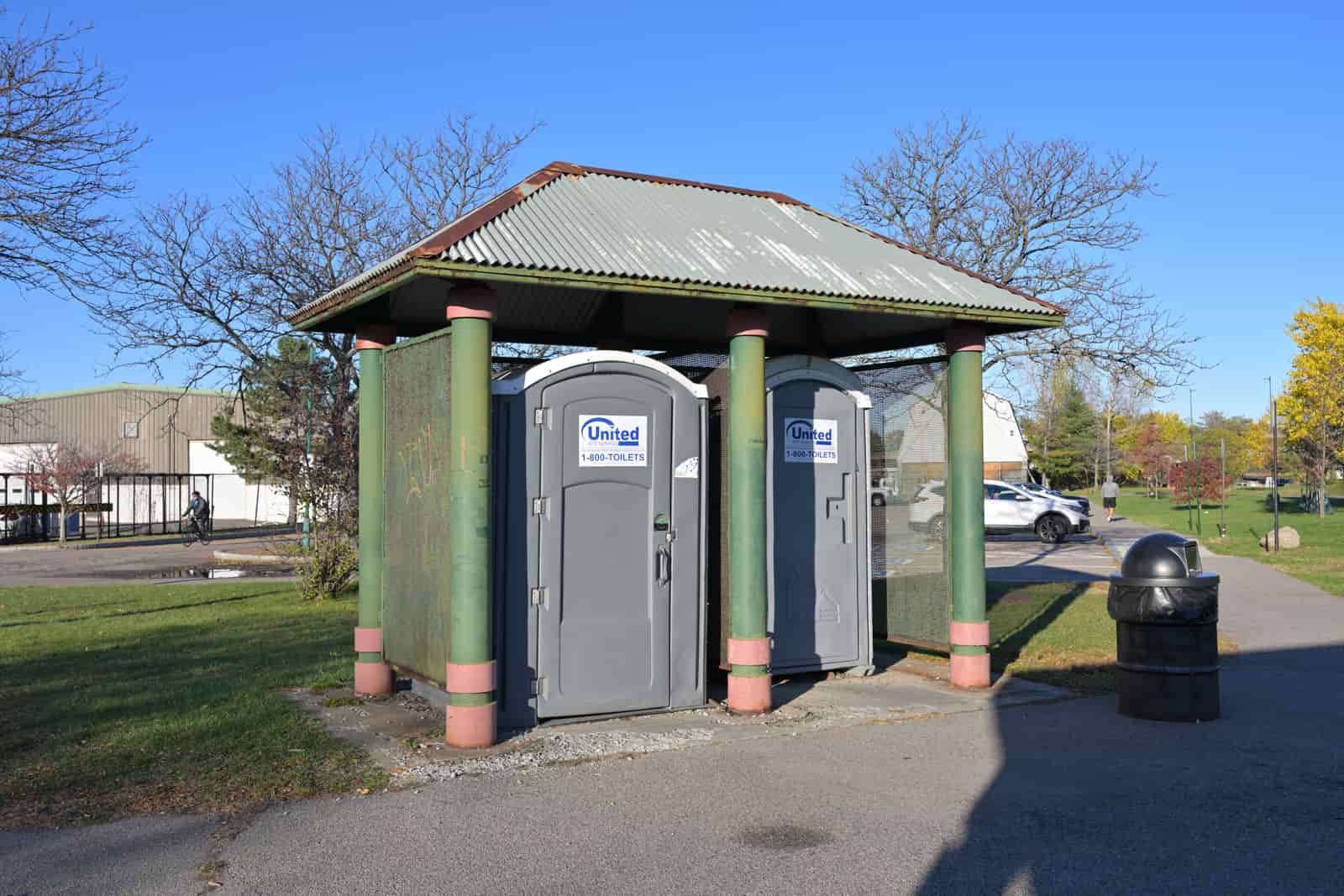 A row of enclosed portable restrooms installed in a public park, illustrative stock photograph