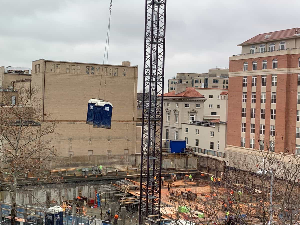 Portable restroom units being lifted by crane at a construction site, illustrative stock photograph