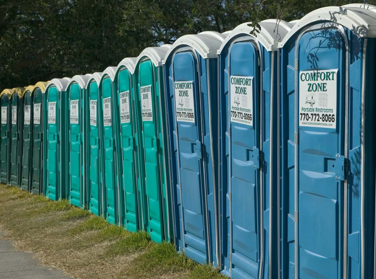A long line of portable restrooms installed at a hurricane response base camp for rescue workers and volunteers, illustrative stock photograph