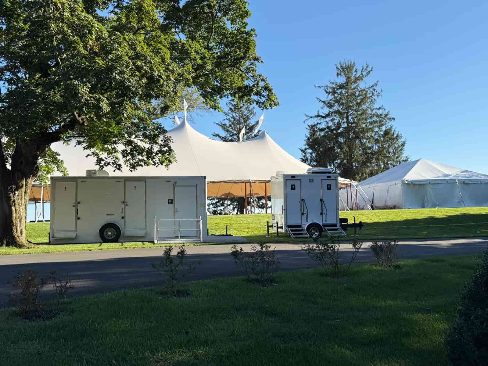 Multiple restroom trailers positioned side by side to serve a large outdoor event, illustrative stock photograph
