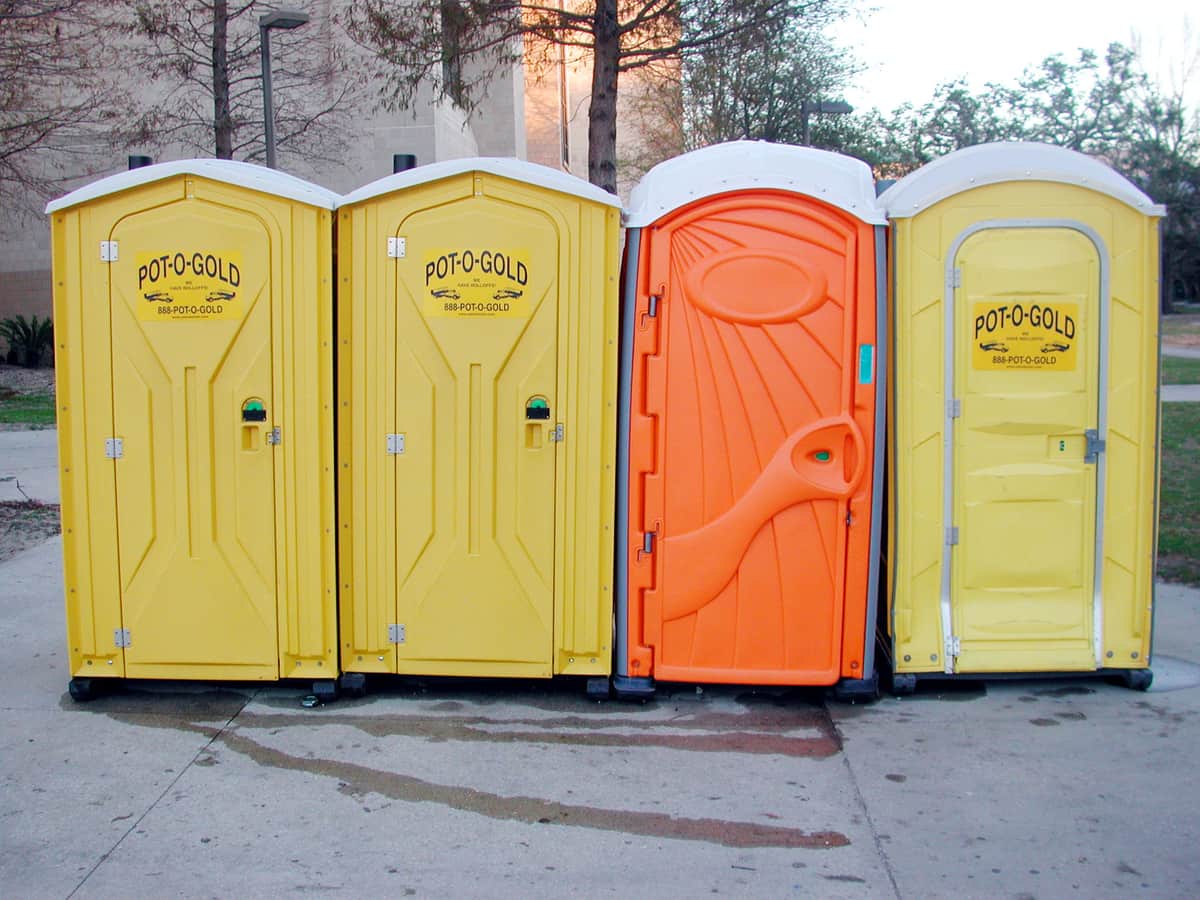 Four portable restroom units lined up along a kerb on a university campus, illustrative stock photograph